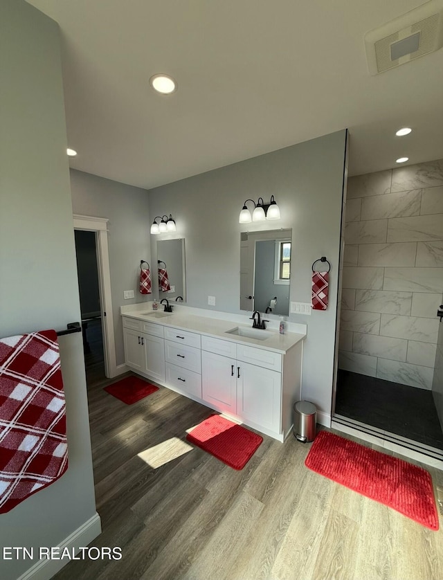 bathroom with vanity, wood-type flooring, and a tile shower