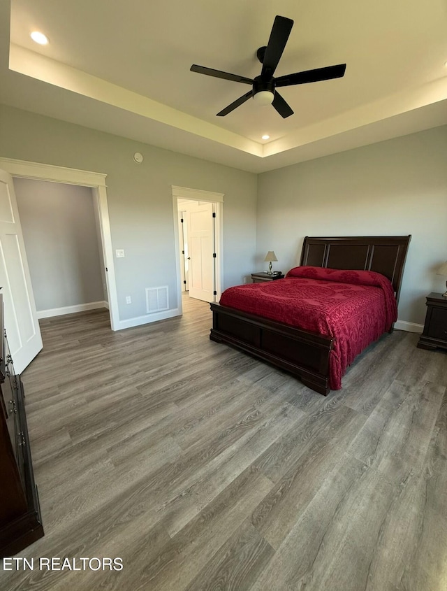 bedroom featuring light hardwood / wood-style floors, a raised ceiling, and ceiling fan