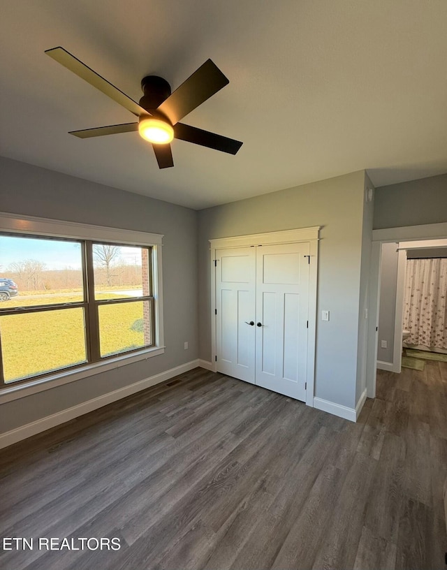 unfurnished bedroom featuring ceiling fan, dark hardwood / wood-style flooring, and a closet