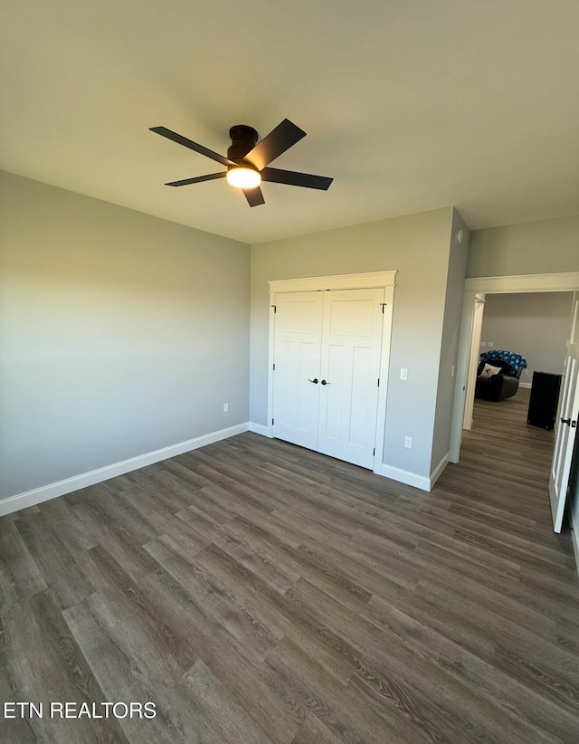 unfurnished bedroom with dark wood-type flooring, ceiling fan, and a closet