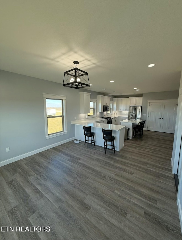 kitchen featuring a kitchen island, a breakfast bar, decorative light fixtures, white cabinets, and stainless steel appliances