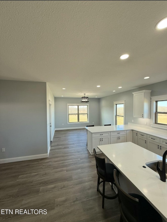 kitchen featuring white cabinetry, a kitchen bar, kitchen peninsula, and plenty of natural light