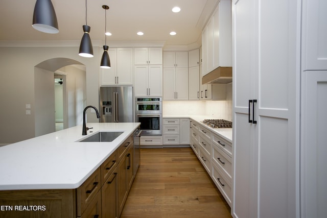 kitchen featuring white cabinetry, stainless steel appliances, decorative light fixtures, and sink