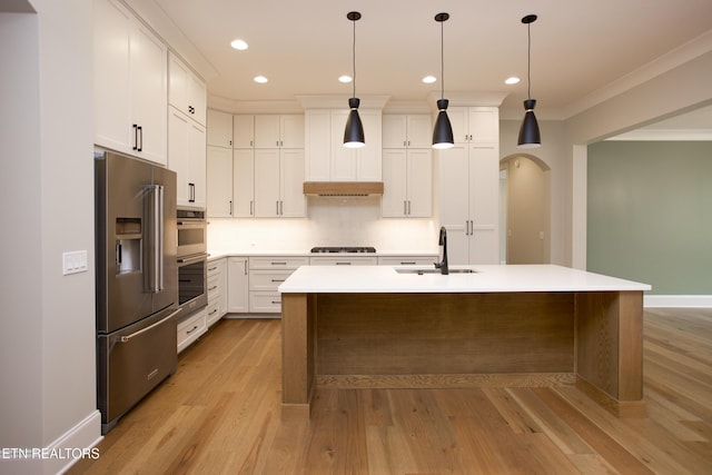 kitchen with decorative light fixtures, an island with sink, sink, white cabinets, and stainless steel appliances