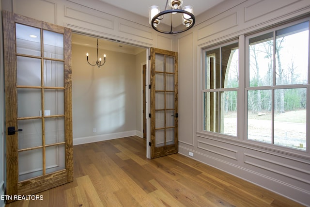 unfurnished dining area with an inviting chandelier and hardwood / wood-style flooring