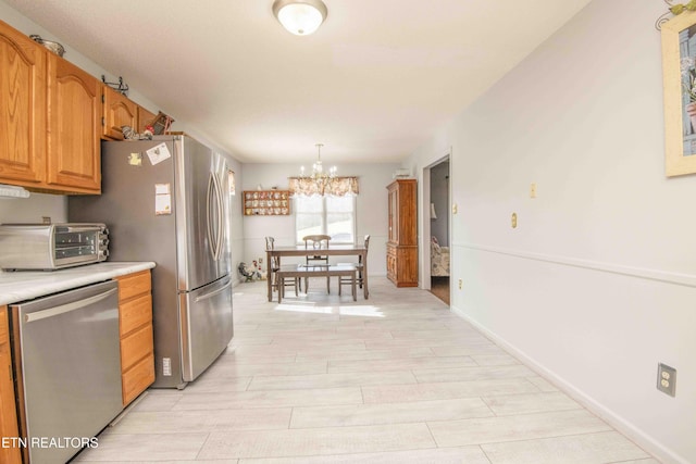 kitchen featuring pendant lighting, appliances with stainless steel finishes, a chandelier, and light wood-type flooring