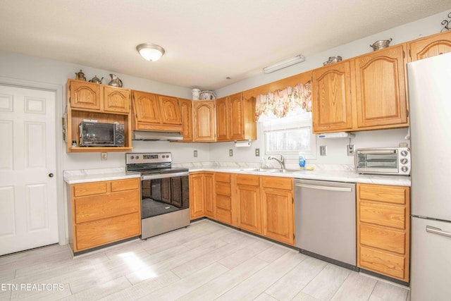 kitchen with stainless steel appliances, sink, and light wood-type flooring