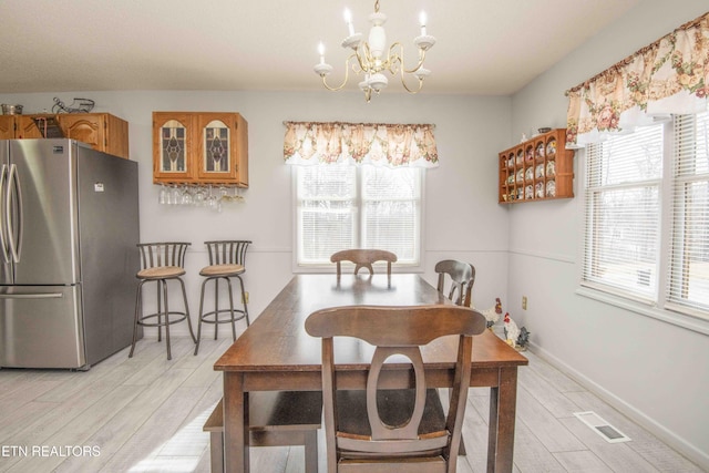 dining area featuring a healthy amount of sunlight, a chandelier, and light hardwood / wood-style floors