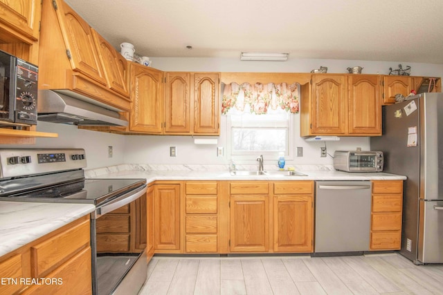 kitchen with appliances with stainless steel finishes, sink, exhaust hood, and light wood-type flooring