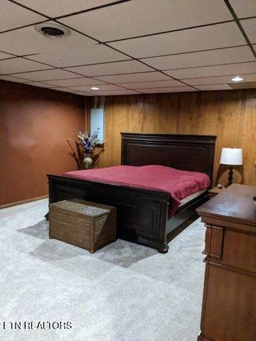 bedroom featuring a paneled ceiling and wood walls