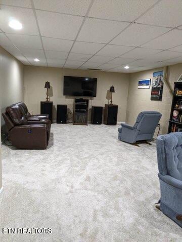 living room featuring carpet floors and a drop ceiling