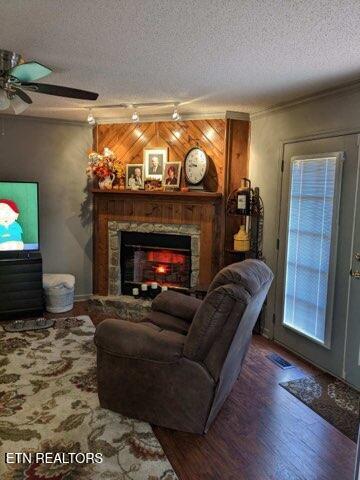 living room with ceiling fan, hardwood / wood-style floors, a textured ceiling, and a fireplace