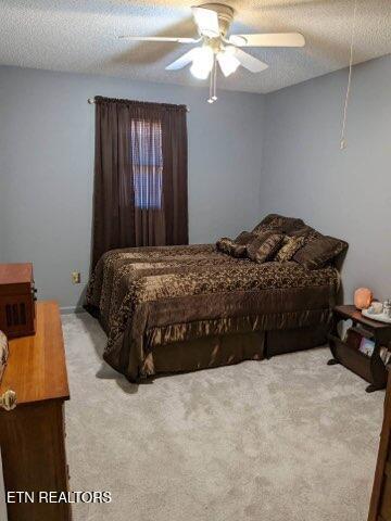 bedroom featuring ceiling fan, light colored carpet, and a textured ceiling