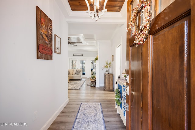 hall featuring hardwood / wood-style flooring, ornamental molding, a chandelier, and beamed ceiling