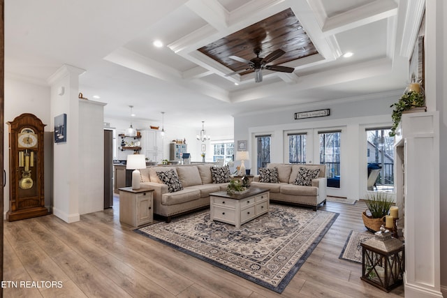 living room with coffered ceiling, ornamental molding, light hardwood / wood-style floors, beam ceiling, and ceiling fan with notable chandelier