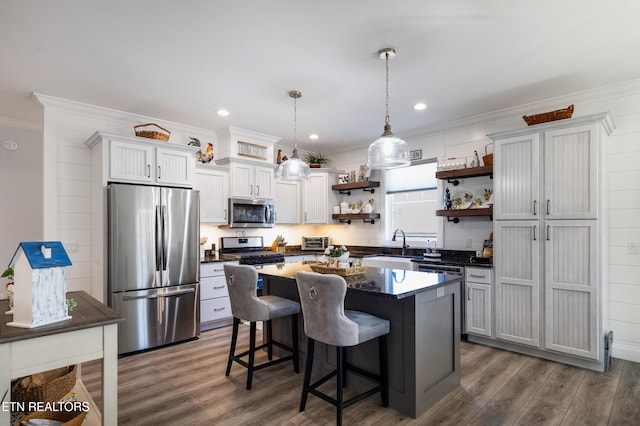 kitchen featuring a kitchen island, decorative light fixtures, a kitchen breakfast bar, stainless steel appliances, and crown molding