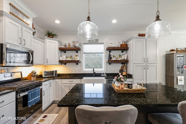 kitchen featuring sink, decorative light fixtures, stainless steel appliances, and a center island