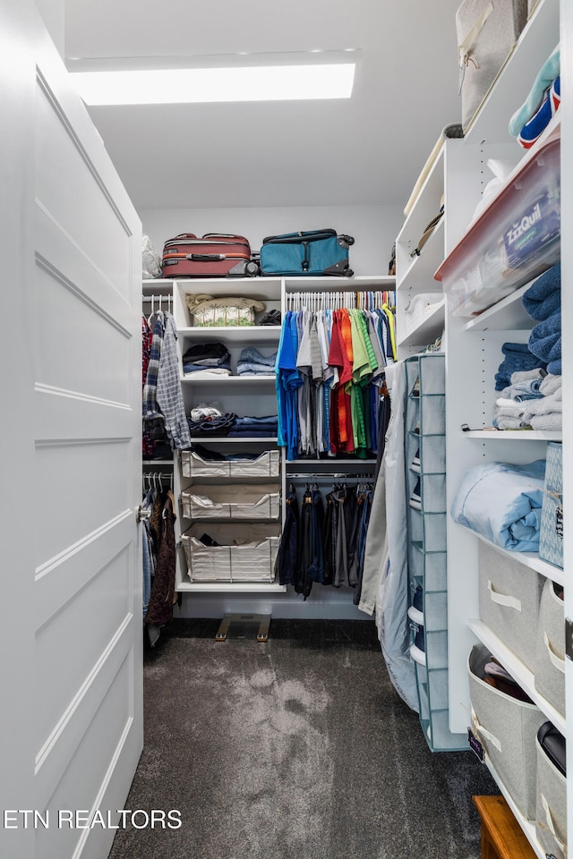 walk in closet featuring dark colored carpet