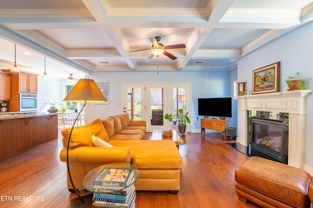 living room featuring beam ceiling, coffered ceiling, a ceiling fan, and wood finished floors