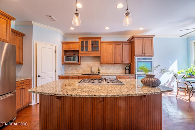 kitchen with brown cabinets, a breakfast bar, a sink, wood finished floors, and stainless steel appliances