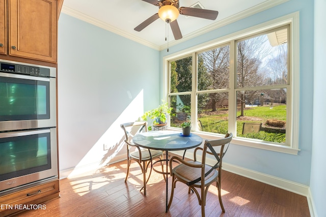 dining area featuring wood finished floors, a ceiling fan, baseboards, and ornamental molding