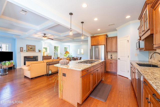 kitchen with brown cabinetry, visible vents, a sink, stainless steel appliances, and a wealth of natural light