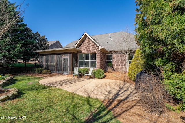 rear view of house with brick siding, a yard, a patio, and a sunroom