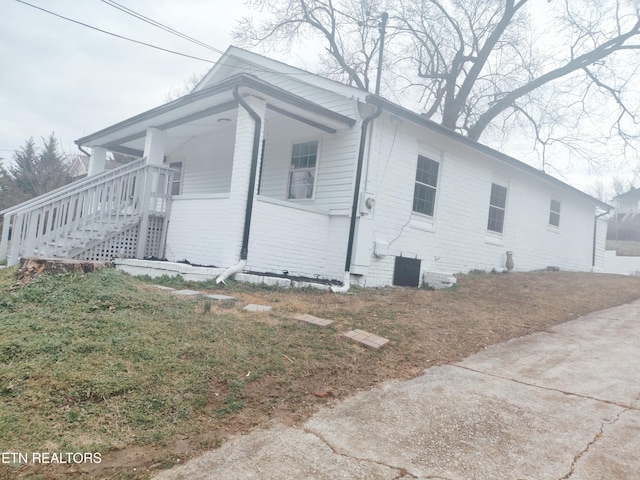 view of side of home with a porch, a yard, and central AC unit