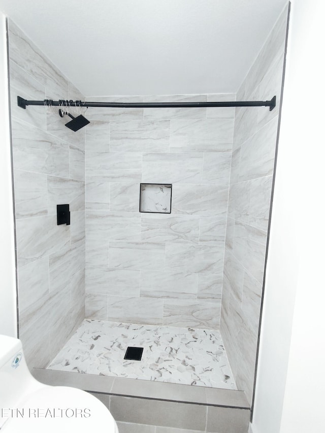 bathroom featuring a tile shower and toilet