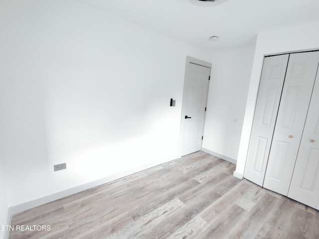 unfurnished bedroom with light hardwood / wood-style floors and a closet