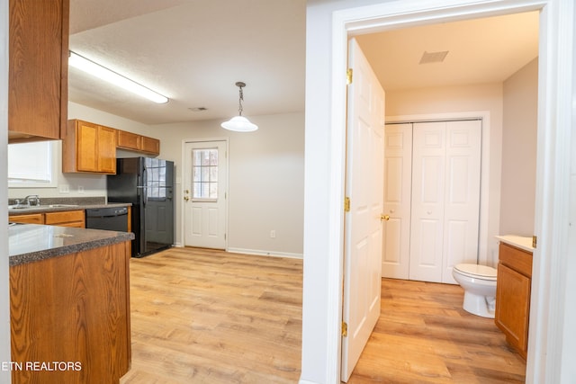 kitchen featuring pendant lighting, sink, light hardwood / wood-style floors, and black appliances