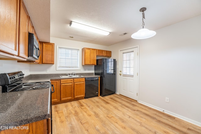 kitchen featuring sink, light hardwood / wood-style flooring, hanging light fixtures, black appliances, and a textured ceiling