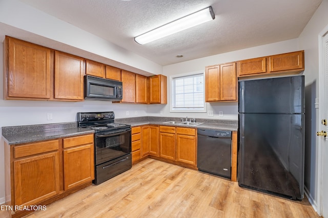 kitchen featuring sink, light hardwood / wood-style flooring, a textured ceiling, and black appliances