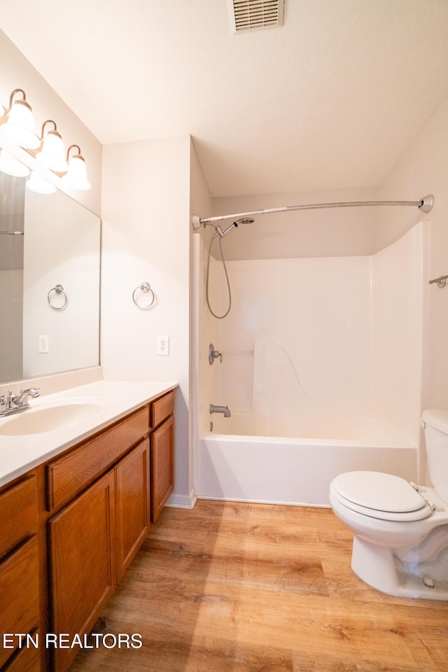 full bathroom featuring hardwood / wood-style flooring, vanity, tub / shower combination, and toilet