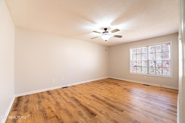 empty room featuring ceiling fan, light hardwood / wood-style floors, and a textured ceiling