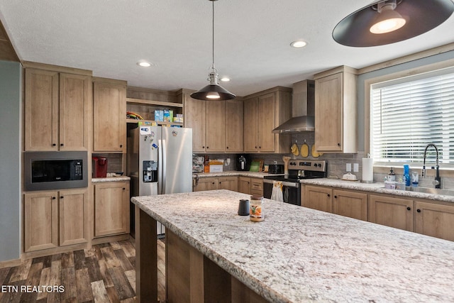 kitchen with wall chimney exhaust hood, sink, decorative light fixtures, appliances with stainless steel finishes, and decorative backsplash