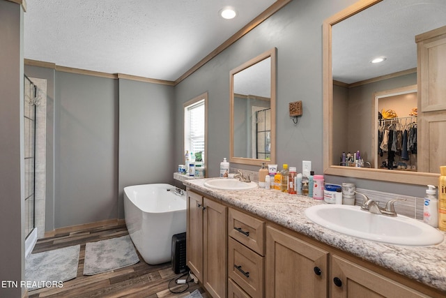 bathroom with vanity, hardwood / wood-style floors, crown molding, and shower with separate bathtub