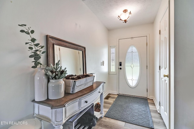 entryway with light hardwood / wood-style floors and a textured ceiling