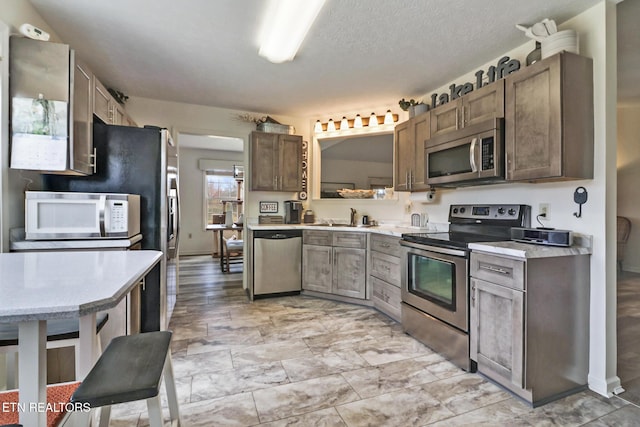 kitchen featuring stainless steel appliances, sink, and a textured ceiling