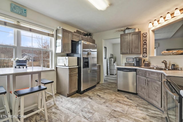 kitchen featuring stainless steel appliances, dark brown cabinets, and sink