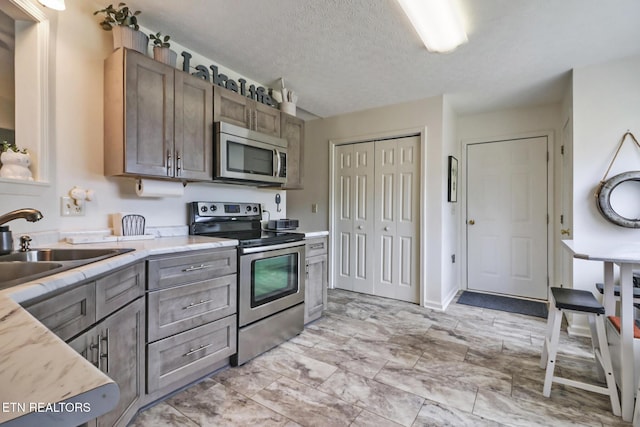 kitchen featuring stainless steel appliances, sink, and a textured ceiling