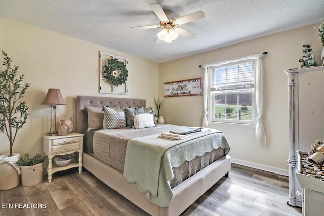 bedroom with ceiling fan, a textured ceiling, and light hardwood / wood-style flooring