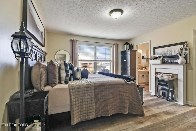 bedroom with hardwood / wood-style floors, a textured ceiling, and ensuite bath