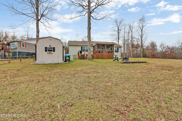 rear view of house with an outdoor fire pit, a yard, an outdoor structure, and a sunroom