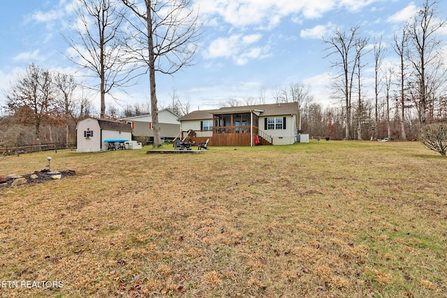 view of front facade featuring a wooden deck, a storage shed, and a front yard