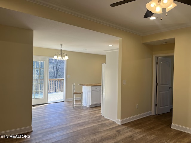 spare room with crown molding, wood-type flooring, and ceiling fan with notable chandelier