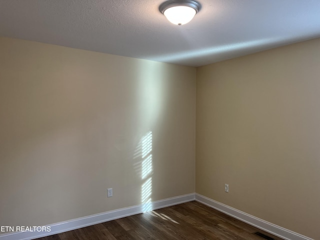 unfurnished room with dark wood-type flooring and a textured ceiling