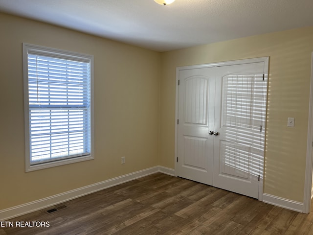 unfurnished bedroom with dark hardwood / wood-style flooring and a closet