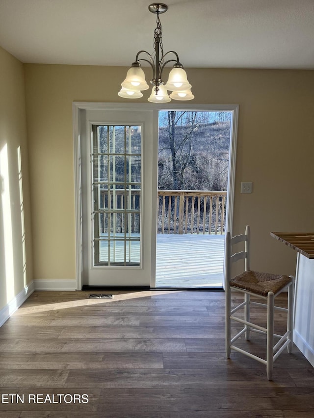 unfurnished dining area with wood-type flooring and a chandelier