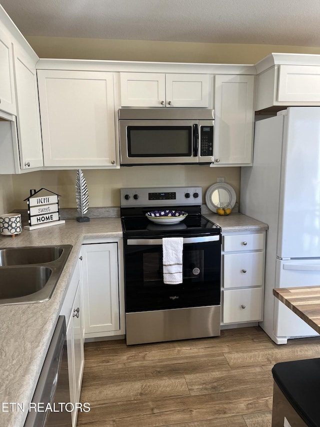 kitchen featuring white cabinetry, stainless steel appliances, sink, and hardwood / wood-style flooring